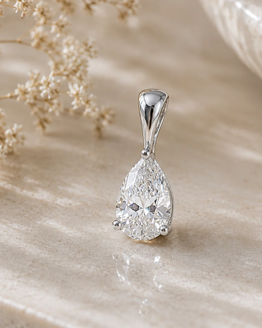 Pear-shaped moissanite solitaire pendant in white gold styled on a counter